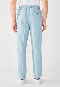 Pantaloni blu chiaro con vestibilità comoda, vita elastica e due tasche posteriori, con dettagli in bottone dorato e una superficie liscia.