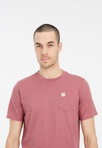 Krátky rukáv, vínová tričko vyrobené z mäkkej tkaniny, s náprsním vreckom a štítkom. Jednoduchý dizajn s okrúhlym výstrihom.