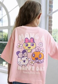 Lyserød bomulds t-shirt med tegneseriefigurer og teksten "HAV EN GLAD DAG." Designet inkluderer pastelfarver og legende blomsterdetaljer.