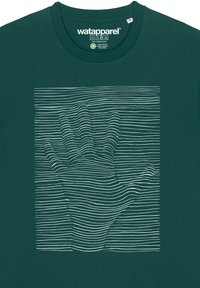 Groene katoen t-shirt met een witte, golvende lijnafbeelding van een hand in het midden, tegen een effen groene achtergrond.