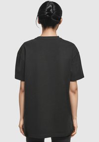 T-shirt noir oversize à manches courtes, col rond, en tissu doux et à coupe décontractée. Pas de motifs ni de graphismes visibles.