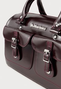 Burgundia faux nahast käekott topeltes esipockets, hõbedased detailid ja kontrastsed roosa õmblused. Omab ümarate käepidemete ja brändi logo.