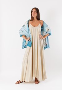 Abito maxi senza maniche beige abbinato a un kimono floreale blu. L'abito ha una forma fluida, mentre il kimono presenta una texture setosa e vivaci motivi.