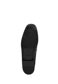 Suela de zapato de cuero negro con banda de goma, que presenta patrones texturizados, un diseño curvado y un logotipo en relieve para mayor tracción y estilo.