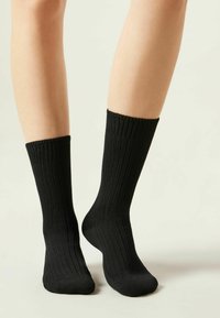 Calze nere a coste con una texture morbida, caratterizzate da un bordo confortevole in cima e una forma adattata, progettate per un uso quotidiano.