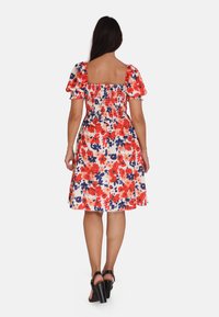 Vestido floral con corpiño fruncido, mangas cortas abullonadas y falda acampanada en patrones rojos, rosas y azul marino sobre un fondo claro.