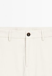 Lichtbeige broek met een rechte snit. Voorzien van een knoopsluiting, een riemlus en nette stiksels. De stof lijkt glad en duurzaam.