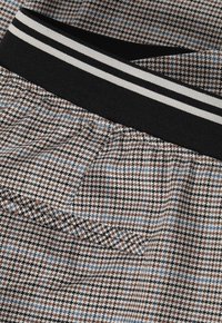 Shorts à carreaux en marron, noir et bleu clair, dotés d'une taille élastique avec des rayures noir et blanc et d'une coupe ample.