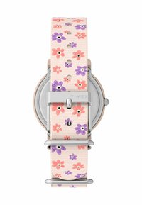 Timex pulkstenis ar rozā ziedu raksta siksniņu, kurā redzami purpursarkani un rozā ziedi. Korpuss ir sudraba tonī ar metāla apdari.