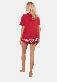 Czerwona bawełniana koszulka z krótkim rękawem w połączeniu z szortami w czerwono-białe serca z falbanami na brzegach.