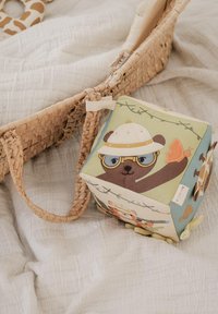 Puha anyagból készült játékkocka, rajzolt állatfigurákkal, pasztell zöld, barna és krémszínben, egy kalapos medvét és egy pillangót ábrázolva.