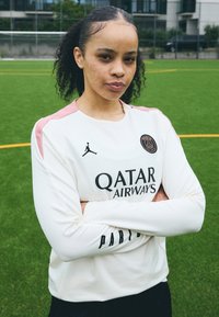 Fehér, hosszú ujjú mez rózsaszín vállbetétekkel és fekete logó részletekkel, rajta a "Qatar Airways" és a "Párizs" felirattal, zöld mezőn viselve.