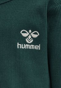 Grøn ribbet stof har et hvidt broderet logo med et stiliseret bi-design og ordet "hummel" nedenunder.