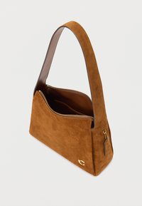 Hnědá semišová kabelka přes rameno s širokým popruhem, zlatým zipem, vnitřní kapsou a malým zlatým logem na předním rohu.