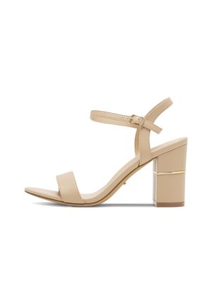 Beżowe lakierowane sandały na obcasie z szerokim paskiem na palce i regulowanym paskiem na kostkę, z kwadratowym obcasem z złotym akcentem.