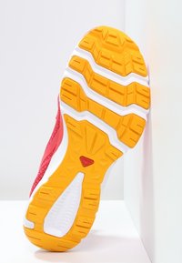 Röd atletisk skosula med ett texturerat mönster, orange detaljer och en vit mellansula, designad för grepp och stabilitet.