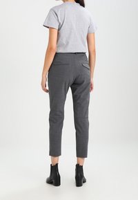 Grå avslappnad t-shirt i kombination med skräddarsydda grå byxor. Byxorna har en bakficka, är figursydda vid ankeln och kompletteras av svarta ankelstövlar.