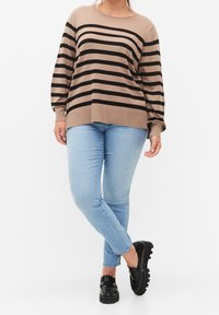 Pull rayé marron et noir au fit décontracté, encolure ronde et poignets côtelés, associé à un jean bleu clair et des mocassins noirs.