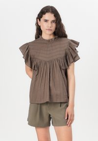 Bruine blouse met gerimpelde mouwen, gestructureerde strepen, ronde halslijn en geplooide details, gecombineerd met olijfgroene shorts.