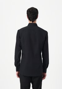 Black long-sleeve shirt made from a smooth fabric, featuring a classic collar and button cuffs, with a tailored fit and a curved hem.