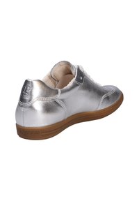 Silverfärgade metalliska sneakers med en slät yta, rund tå och vita snörningar. Har en tanfärgad gummisula och diskret märkning på hälen.