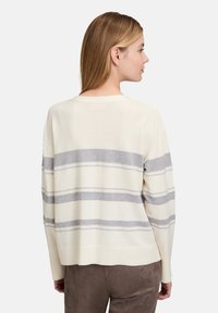 Helle beigefarbene Pullover mit grauen Streifen, im lässigen Schnitt, mit weiten Ärmeln und geripptem Saum. Aus weichem Strickstoff mit sichtbarer Textur.