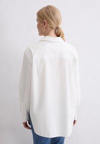 Witte lange mouw blouse met een kraag, met een rechte rugzoom en een licht oversized pasvorm, gemaakt van gladde stof.