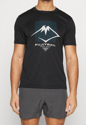 Mann trägt schwarzes T-Shirt mit weißem Bergmotiv, blauer Raster-Hintergrund, Schriftzug "FUJITRAIL" und graue Shorts vor hellem, einfachem Hintergrund.