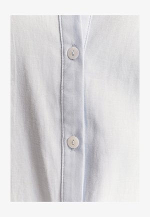 Svijetloplava traper košulja s mekom teksturom, vertikalnim šavovima i bijelim gumbima duž prednjeg dijela.