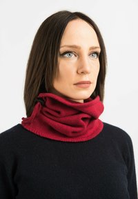 Rød strikket cowl neck varme med en blød tekstur, der har et dobbeltlagsdesign og syede kanter, båret over en mørk sweater.