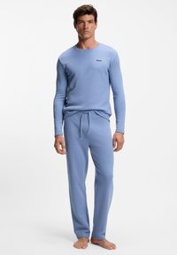 Lichtblauw loungewear-set van een gestructureerde stof, bestaande uit een longsleeve met ronde hals en broek met elastische taille en trekkoord.