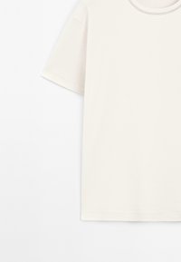 T-shirt di cotone bianco con collo rotondo, maniche corte e una texture liscia. Nessun motivo o dettaglio visibile.