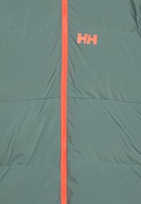 Padded bunda v tealovej farbe s oranžovým zipsom a logom. Má horizontálne prešívanie a hladkú, ľahkú textúru.