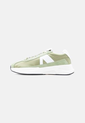 Jasnozielony niski tenisówka z białymi akcentami, grubą białą podeszwą i sznurowanym fasonem, pokazana z boku na jednolitym tle.