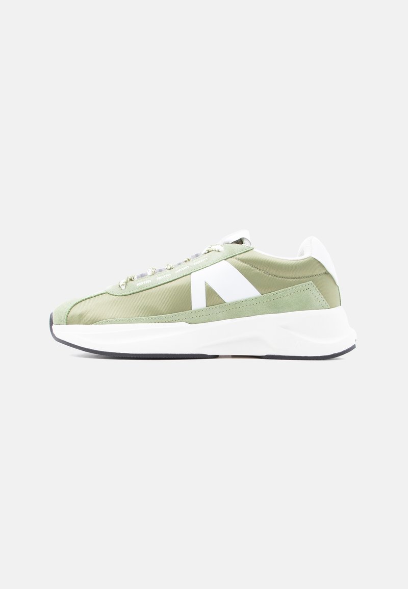 Baskets basses vert clair avec accents blancs, semelle épaisse blanche et design à lacets, vues de côté sur un fond uni.