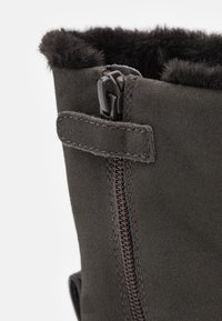 Mörkgrå mockastövlar med dragkedja och mjuk pälsdetalj upptill. Utsmyckade med en stickad detalj nära dragkedjan.