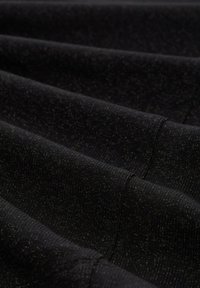 Schwarzer Strickstoff mit einer strukturierten Oberfläche, die einen dezenten metallischen Glanz aufweist. Die Oberfläche zeigt horizontale Falten und Nähdetails.