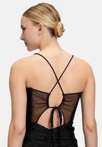 Czarna sukienka z przezroczystym panelem na plecach, krzyżującymi się ramiączkami oraz marszczonymi detalami. Gładka tekstura z subtelnym połyskiem.