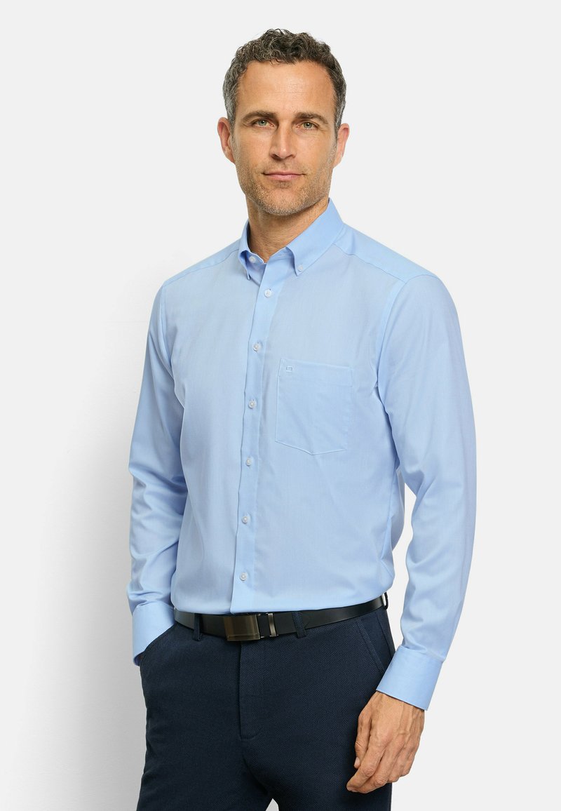 Camicia azzurro chiaro a maniche lunghe con bottoni, dotata di una tasca sul petto, in tessuto morbido e con colletto strutturato, abbinata a pantaloni scuri e una cintura nera.
