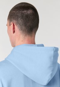 Felpa blu chiaro con cappuccio a cordino e polsini a coste, realizzata in morbido cotone con una texture liscia.