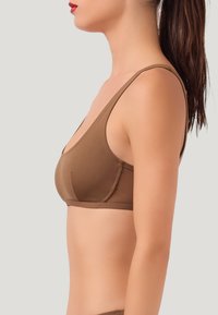 Reggiseno marrone senza cuciture con scollatura profonda, spalline larghe e texture morbida. Design semplice senza decorazioni o motivi.