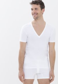 Weißes Kurzarm-V-Ausschnitt-Shirt aus glattem Stoff, kombiniert mit weißen Shorts. Schlichtes Design, enganliegende Form, keine sichtbaren Muster oder Hardware.