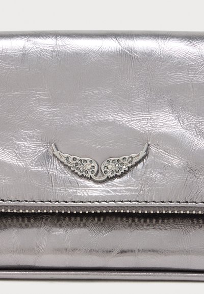 Plånbok i silvermetall med texturerad yta, utrustad med en silveraccent i form av en vinge i mitten. Dragkedjedetalj längs nederkanten.