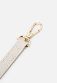 Sangle blanche texturée avec un fermoir pivotant en métal doré et un crochet à ressort pour attacher aux sacs ou accessoires.