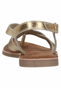 Gouden metallic sandalen met bandjes en een vlakke beige zool, voorzien van een gestructureerde voetbed en een verstelbaar enkelbandje. Eenvoudig en open ontwerp.