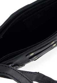 Black leather handbag with a zippered opening, featuring a smooth texture, internal lining, and metal snap closures on the outer flap.