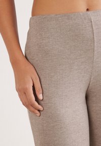 Hellbraune Leggings aus einem weichen, strukturierten Stoff mit einem glatten Bund, figurschmeichelnder Passform und minimalistischen Designdetails.
