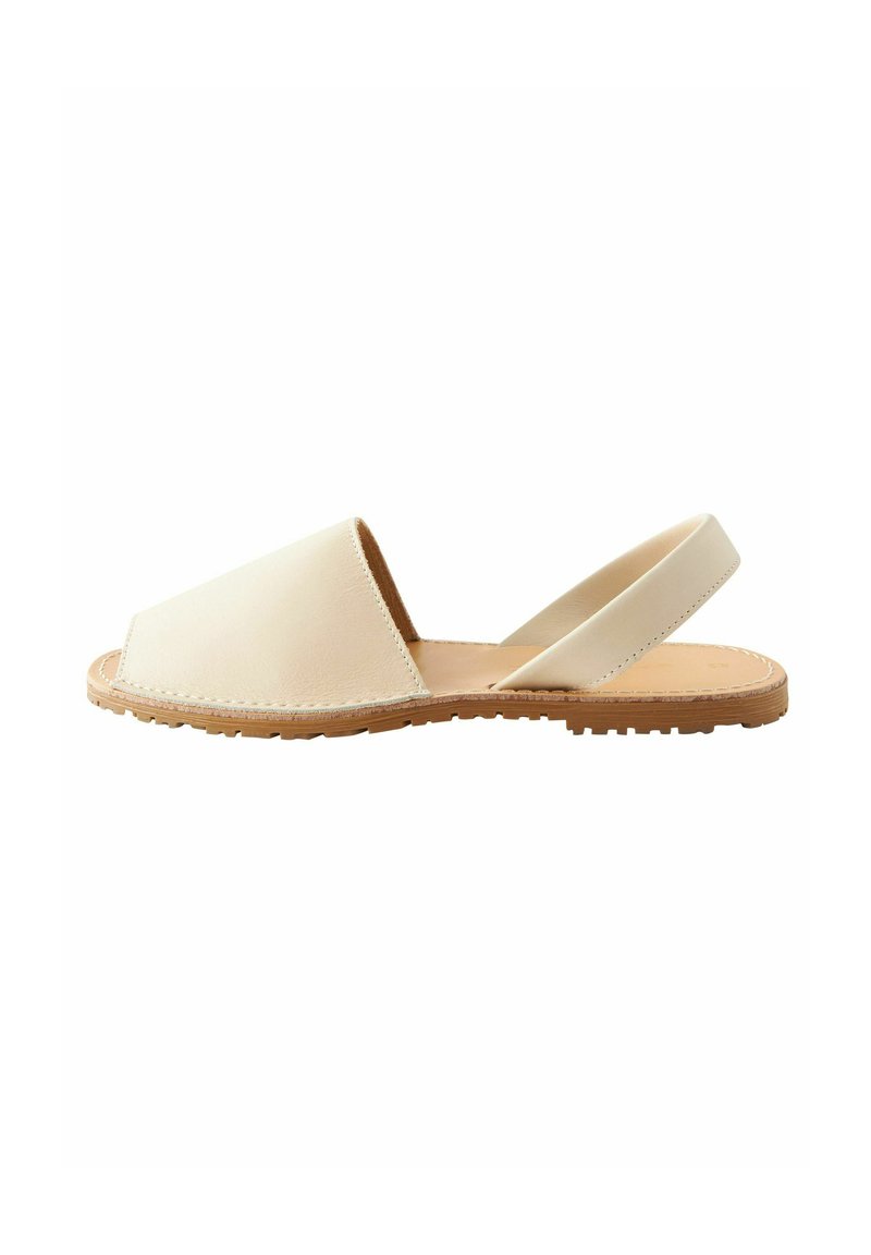 Sandalo slingback in pelle color crema con punta quadrata, suola piatta e cuciture visibili. Superficie testurizzata abbinata a un interno liscio.