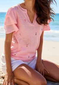 Top de punto rosa de mangas cortas con escote en V, que presenta diseños bordados de helados y dulces. Tejido texturizado con escote con forma de ondas.