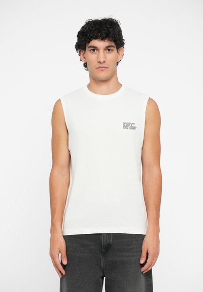 T-shirt sans manches blanc en coton, avec un petit graphique en texte noir sur la poitrine gauche. Texture lisse, col rond.